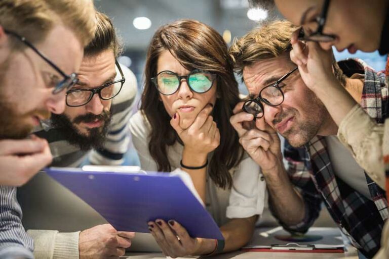 Team betrachtet skeptisch und dicht zusammen gedrängt eine Notiz