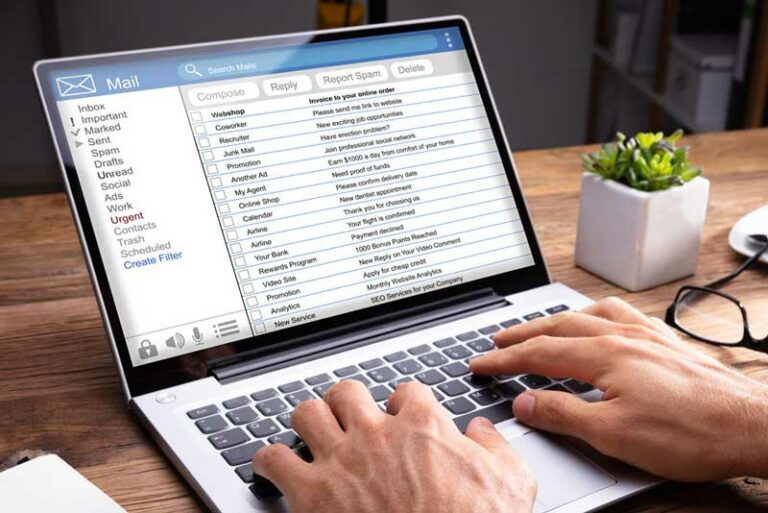 Hände am Laptop auf Schreibtisch mit einem E-Mail-Postfach auf dem Display