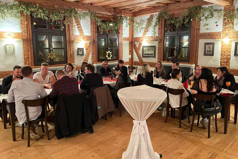 Team der Interactive One sitzt im Gasthaus an weihnachtlich, gedeckter Tafel