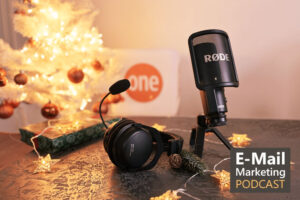Foto von einem Podcastmikrofon und Kopfhörer die auf einem Tisch stehen und im Hintergrund leuchtet ein kleiner Weihnachtsbaum mit orangenen Kugeln.