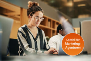 Junge Frau arbeitet konzentriert an einem Laptop in einer modernen Agentur.